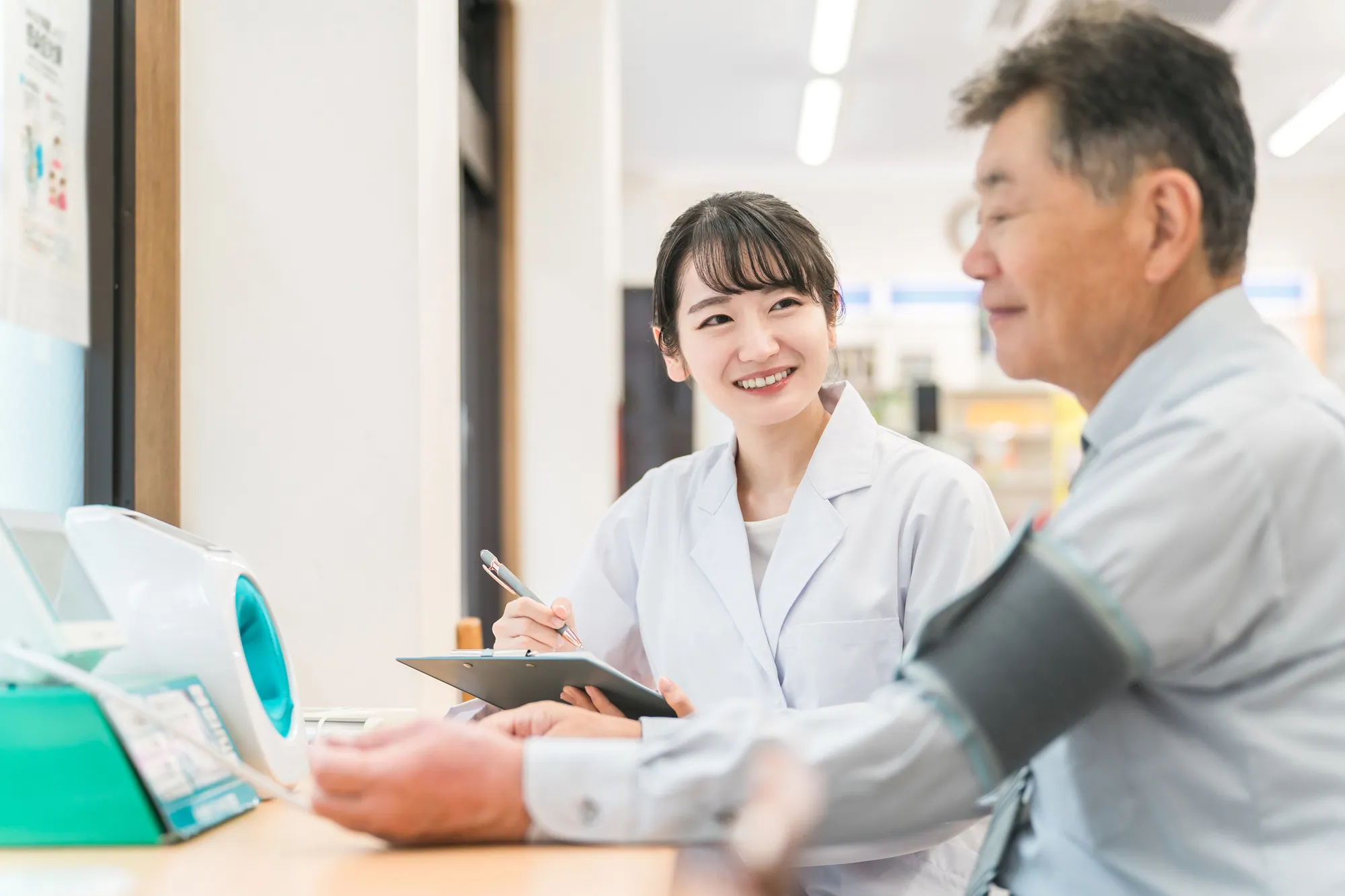 血圧を測る受診者と記録する看護師の写真